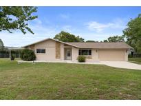 Charming single-story home featuring stone accents, a covered carport, and a well-maintained front lawn at 10441 Mayflower Rd, Spring Hill, FL 34608
