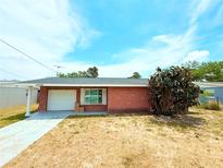 Charming single-story red brick home featuring an attached garage and a well-maintained lawn at 11034 Harding Dr, Port Richey, FL 34668