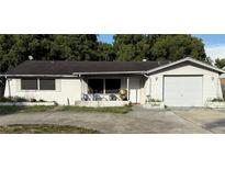 Cozy one story home featuring a front yard, an attached garage, and a front porch with lawn chairs at 11726 Oceanside Dr, Port Richey, FL 34668