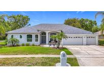 Charming single-story home with manicured lawn, palm trees, and a three-car garage at 18902 Saint Laurent Dr, Lutz, FL 33558
