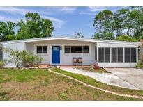 Charming single-story home featuring a bright blue front door and a cozy screened-in porch at 2012 Warrington Way, Tampa, FL 33619