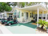 Charming home exterior featuring a covered porch, well-manicured landscaping, and a convenient golf cart parking area at 21040 Lazy Days Cir, Lutz, FL 33558