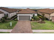 Charming single-story home featuring a two-car garage, tile roof, brick driveway, and manicured landscaping at 3051 Francoa Dr, Odessa, FL 33556