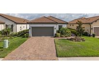 Charming single-story home with a brick driveway and well-manicured landscaping and gray garage door at 3051 Francoa Dr, Odessa, FL 33556