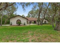 Charming home featuring a well-manicured lawn, a circular driveway, and a unique architectural design at 4595 Lake In The Woods Dr, Spring Hill, FL 34607
