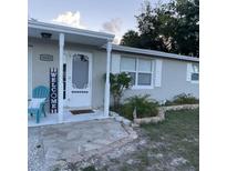 Inviting front entrance with stone pathway, blue welcome chair and neatly kept landscaping at 6603 Adams St, New Port Richey, FL 34652