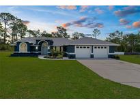 Beautiful single-story home with a well-manicured lawn, arched entryway, and attached three-car garage at 8084 Nightingale Rd, Weeki Wachee, FL 34613
