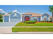Charming single-story home with a well-manicured lawn, red front door, and attached two-car garage at 10250 Locker Dr, Spring Hill, FL 34608
