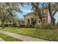 Elegant two-story home featuring a stucco exterior, arched entryway, balcony, and professionally landscaped front yard at 10531 Pontofino Cir, Trinity, FL 34655