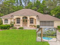Charming single-story home featuring a lush green lawn, a screened garage, and a screened in pool at 12805 Coronado Dr, Spring Hill, FL 34609