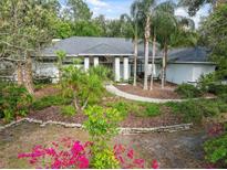Charming home featuring meticulous landscaping with mature trees, lush flower beds, and a neatly manicured lawn at 1471 N Jasmine Ave, Tarpon Springs, FL 34689