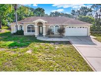 Charming single-story home features a well-manicured front yard, arched windows, and attached two-car garage at 2172 Whitewood Ave, Spring Hill, FL 34609