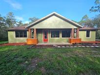 Charming single-story home featuring a welcoming red front door and delightful flower box accents at 34335 Berryhill Dr, Webster, FL 33597