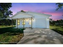 Charming single-story home featuring white siding, a covered porch, and an attached garage at 3554 Arrowhead Ave, Spring Hill, FL 34606