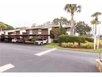 Exterior view of the apartment building with carports and lush landscaping at 4008 Passport Ln # 104, New Port Richey, FL 34653