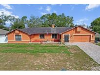 Charming single-story home with an orange exterior, brick driveway, and a well-maintained front lawn at 4289 Castle Ave, Spring Hill, FL 34609