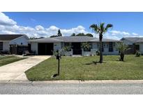 Charming home featuring an inviting front yard with lush greenery and a palm tree, creating a tropical ambiance at 7534 Briarwood Dr, Port Richey, FL 34668