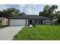 Charming single-story home featuring a well-manicured lawn, freshly painted exterior, and a spacious two-car garage at 12064 Cradock St, Spring Hill, FL 34608