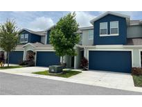 Beautiful townhome featuring a blue garage door, modern architecture and a manicured lawn at 1508 Figleaf Ln, Clearwater, FL 33756