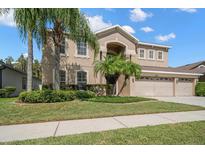 Charming two-story home with a three-car garage, lush landscaping, and beautiful palm trees at 17905 Machair Ln, Land O Lakes, FL 34638