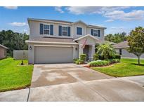 Charming two-story home features a manicured lawn, gray siding, blue shutters and an attached two car garage at 18566 Hunters Meadow Walk, Land O Lakes, FL 34638