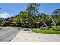 Exterior shot of the building with a beautiful well-maintained landscape, including mature trees and manicured shrubs at 1934 Golfview Dr # 1934, Tarpon Springs, FL 34689