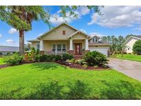 Charming single-story home featuring a well-manicured lawn, covered porch, and lush landscaping at 19531 Mossy Oak Ct, Brooksville, FL 34601