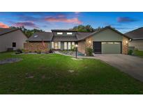 Charming single-story home featuring a landscaped front yard, brick accents, and a two-car garage at 35046 Smoketree Ln, Dade City, FL 33523