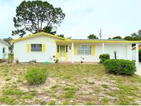 Charming white home with yellow trim and shutters, complemented by a well-maintained yard at 4142 Crestfield Ave, Holiday, FL 34691