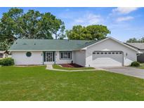 Charming single-story home with a green roof, well-maintained lawn, and attached two-car garage at 5035 Harbinger Rd, Spring Hill, FL 34608