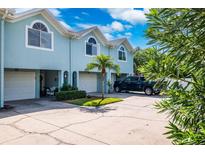 Charming blue townhome featuring an attached garage, well-kept landscaping, and a private driveway at 639 Garland Cir, Indian Rocks Beach, FL 33785