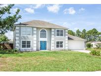 Inviting two-story home featuring a bright blue front door and a well-manicured lawn at 10386 Norvell Rd, Spring Hill, FL 34608