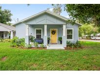 Charming single-story home featuring a yellow front door and beautifully landscaped front yard at 1601 E 98Th Ave, Tampa, FL 33612