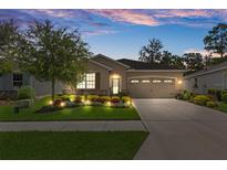 Charming home with a two-car garage, beautiful landscaping, and an inviting, well-lit exterior at 17727 Garsalaso Cir, Brooksville, FL 34604