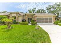 Charming single-story home with a well-manicured lawn and a screened garage in a serene neighborhood at 2481 Whispering Pines Ct, Spring Hill, FL 34606