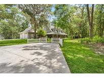 Charming home with a white picket fence, large driveway and lush green lawn at 27091 Country Oak Dr, Brooksville, FL 34602