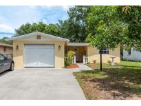 Charming yellow house with a well-maintained front yard and a white garage door at 3140 Bahia Ave, Holiday, FL 34690