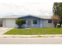 Charming single-story home featuring a blue front facade, well-maintained lawn, and attached garage at 3151 Wellington Dr, Holiday, FL 34691