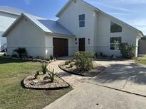 Stunning two-story home featuring a well-manicured yard, lush garden beds, and a charming brick walkway at 4104 Pine Dale Ct, Hernando Beach, FL 34607