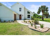 Beautiful two story home with white facade, modern windows, manicured lawn and inviting walkway at 4104 Pine Dale Ct, Hernando Beach, FL 34607