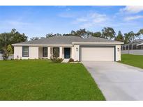 Charming single-story home featuring a well-manicured lawn, a two-car garage, and a welcoming blue front door at 4479 Bluewater Ave, Spring Hill, FL 34606