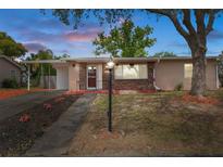 Charming single-story home with a brick facade, mature trees, and a well-maintained front yard and covered carport at 4537 Cynthia Ln, Spring Hill, FL 34606