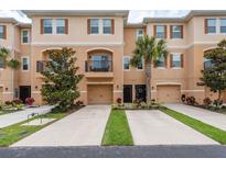 Townhouse exterior with two-car driveways, garages, balcony, neutral paint, dark accents, and manicured landscaping at 5520 White Marlin Ct, New Port Richey, FL 34652