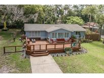 Charming home featuring a spacious deck, outdoor seating, and a landscaped front yard at 7424 Grand Blvd, New Port Richey, FL 34652