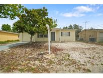 Modest single-story home with a small yard, partial stone ground cover, and mature shade tree at 8053 Dedham Dr, Port Richey, FL 34668