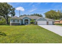 Charming single-story home boasts a manicured lawn, mature trees, and a three-car garage at 9431 Amidon St, Spring Hill, FL 34608