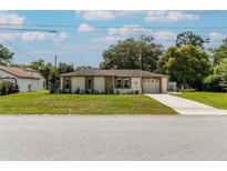 Charming single-story home with a manicured lawn, complemented by a long driveway leading to an attached garage at 9630 Eldridge Rd, Spring Hill, FL 34608
