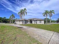 Charming single-story home with a long driveway, three-car garage and lush landscaping at 10941 Hilltop Dr, New Port Richey, FL 34654