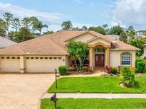 Charming single-story home featuring a well-manicured lawn, a three-car garage, and a welcoming front entrance at 11144 Brambleleaf Way, Hudson, FL 34667