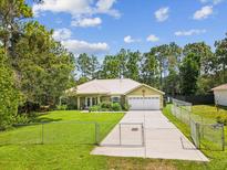 Charming home featuring a metal roof, fenced yard, and well-maintained landscaping, offering curb appeal and security at 12229 Barnevelde Rd, Weeki Wachee, FL 34614